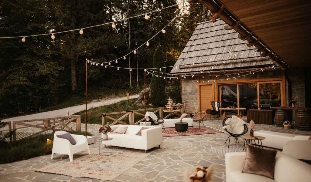 Ena izmed najlepših poročnih lokacij na gorenjskem, Vila Planinka. Na terasi stojijo vrne luči, sedežne garniture, unikatni stoli, cvetje ter akrilne table s kaligrafskimi napisi. Vsa dekoracija je v temi boho poroke, za katero je poskrbela edinstvena Petra Starbek.