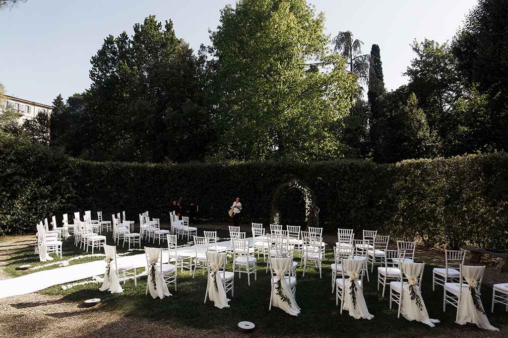 Poročni civilni obred v polkrožni postavitvi s cvetličnim obokom na vrtu prekrasne vile. Foto: Storija weddings