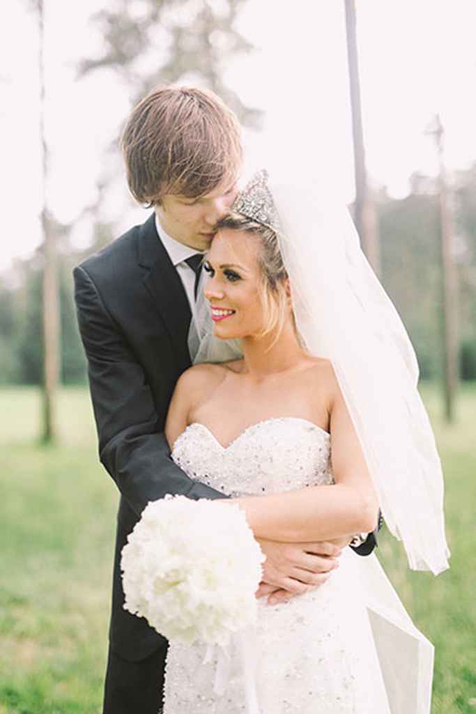 Ženin Jaka Klobučar objema svojo nevesto Dašo, ki nosi prečudovito belo poročno obleko iz poročnega salona Vesna Sposa. V roki drži bel poročni šopek. Foto: Nastja Kovacec Photography