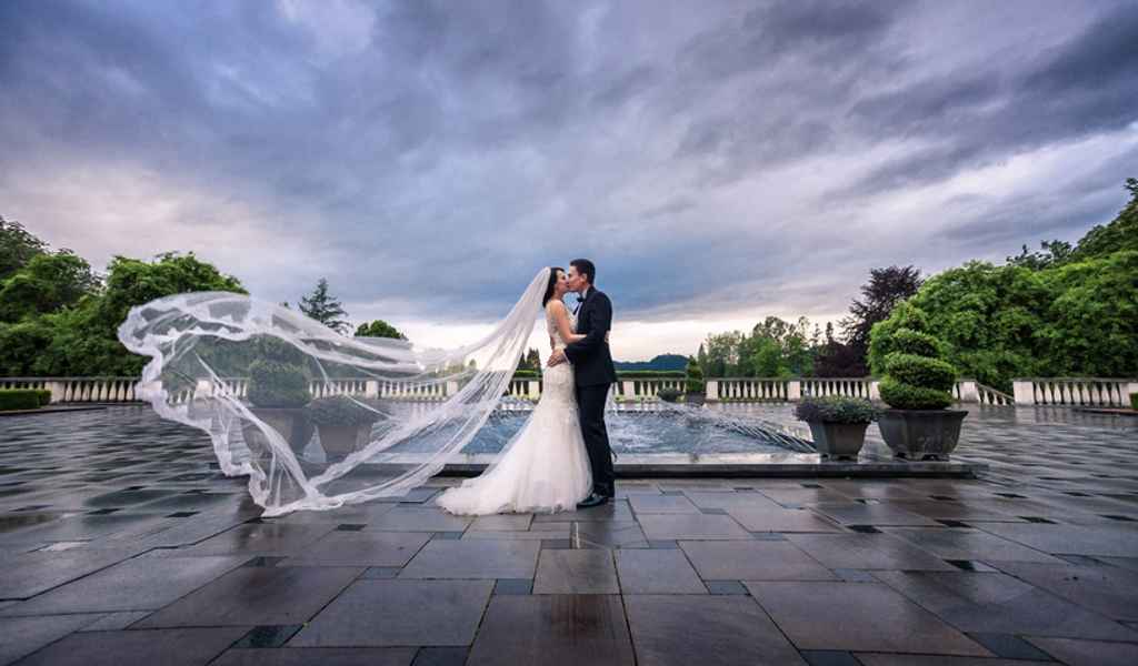 Nevesta in ženin se poljubljata na grajski terasi gradu Brdo pri Kranju. Foto: Ana Gregorič Photography