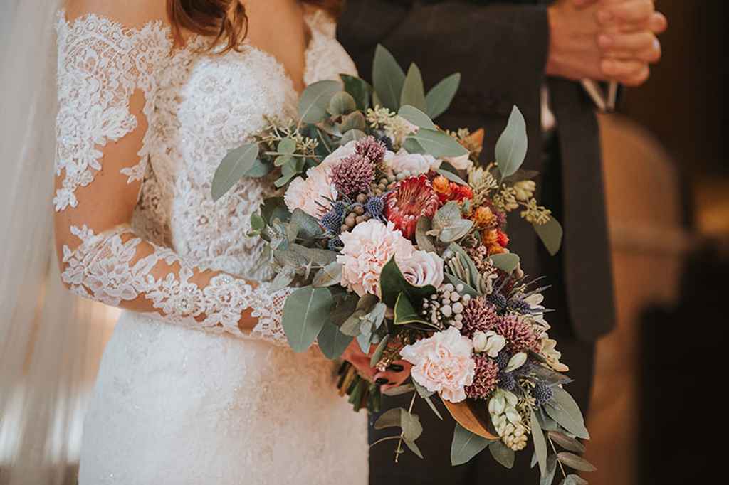 Nevesta drži unikaten poročni šopek v rokah med cerkvenim poročnim obredom. Foto: Ana Gregorič Photography