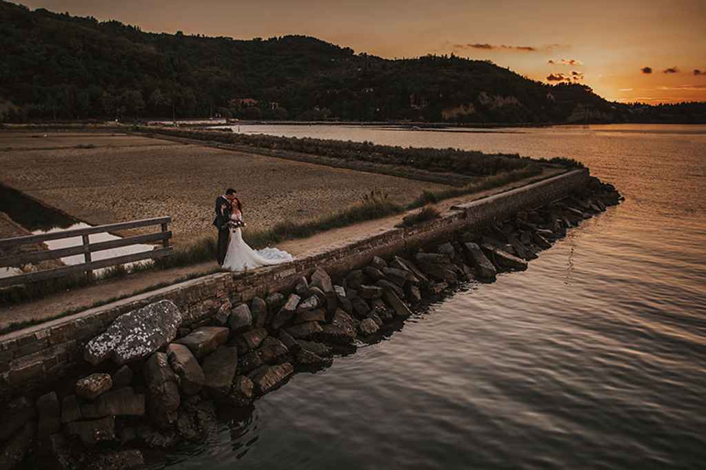 Poročni par se sprehaja na obali med sončnim zahodom v Strunjanu. Foto: Ana Gregorič Photography