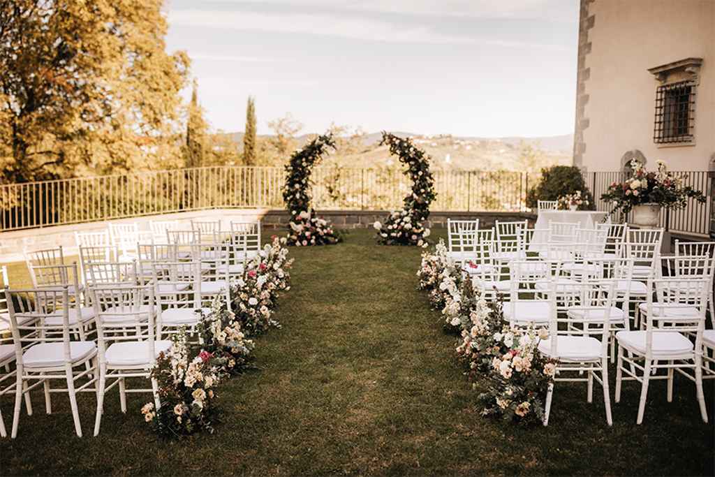 Okrogel cvetlični obok ter nizki cvetlični aranžmaji pri belih lesenih stolih so pričarali čudovito kuliso za civilno poroko v vili Vipolže. Foto: LR weddings