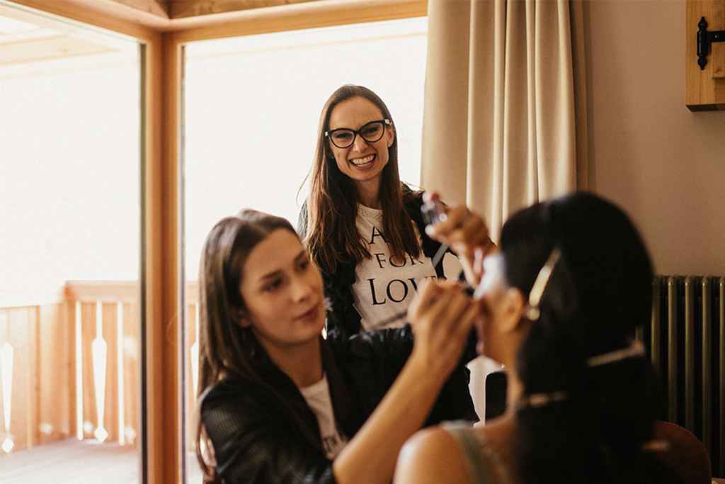 Organizatorka porok Petra Starbek se v nevestini sobi sproščeno pogovarja z nevesto, ki jo liči izkušena poročna vizažistka Maja Drab. Foto: Aluna weddings