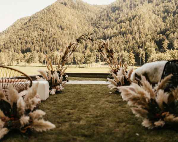 Organizacija boho poroke. Kot glavna poročna dekoracija je bila pampas trava. V ozadju je prečudoviti razgled iz Vile Planinke na Jezerskem. Boho poročni obok iz pampaške trave krasi civilni obred.