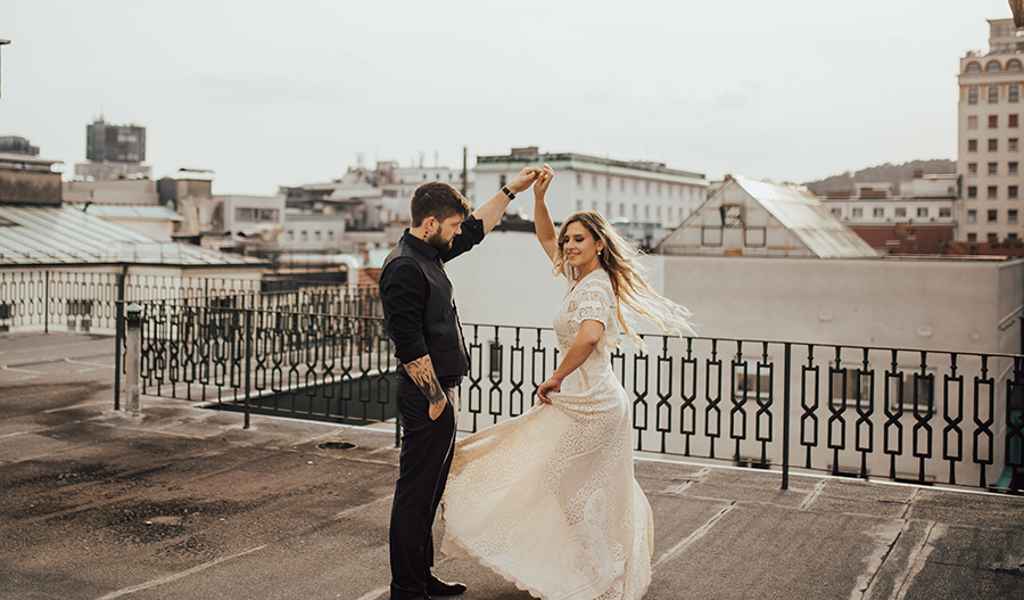 Poročni par po simboličnem civilnem obredu zadovoljno pleše na strehi hotela Union v Ljubljani. Za najboljše poročne ponudnike, ki se ujamejo z vsakim parom, je poskrbela agencija Storija weddings.